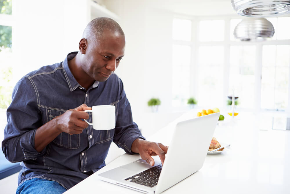 man looking at laptop while drinking coffee